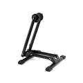The 6MIL BS-01 Bike Stand is a black, heavy-duty stand with foldable metal arms and rubber-tipped feet, shown upright against a white background.