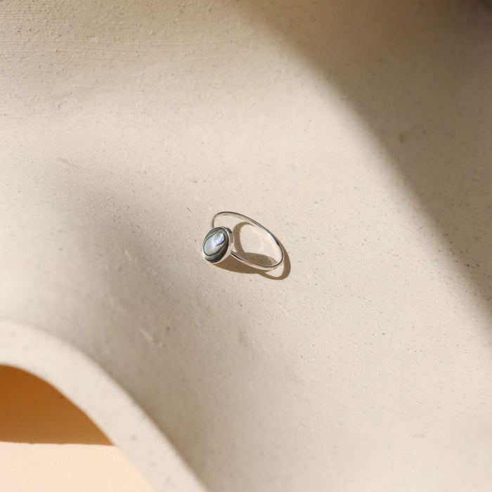 sterling silver ring with handset abalone stone on a light dish