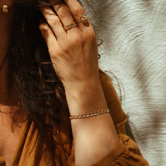 model wearing 14k gold fill rings one with an oval sea jasper stone and a 14k gold fill curb chain bracelet