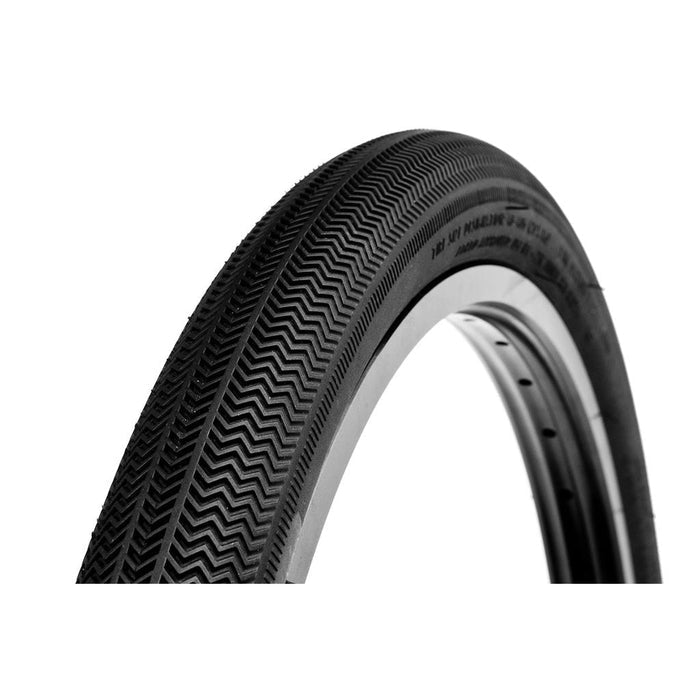 Close-up of the Alienation TCS R1 20 Inch Tyre (Tubeless/Foldable) featuring a chevron tread pattern, partially shown against a white background—ideal for BMX race tyre enthusiasts who want both top performance and standout style.
