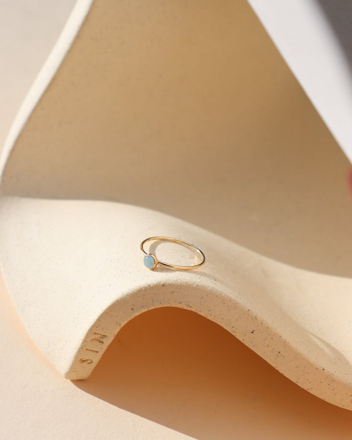 14k gold fill bezel ring setting with 4mm aquamarine stone on a light dish