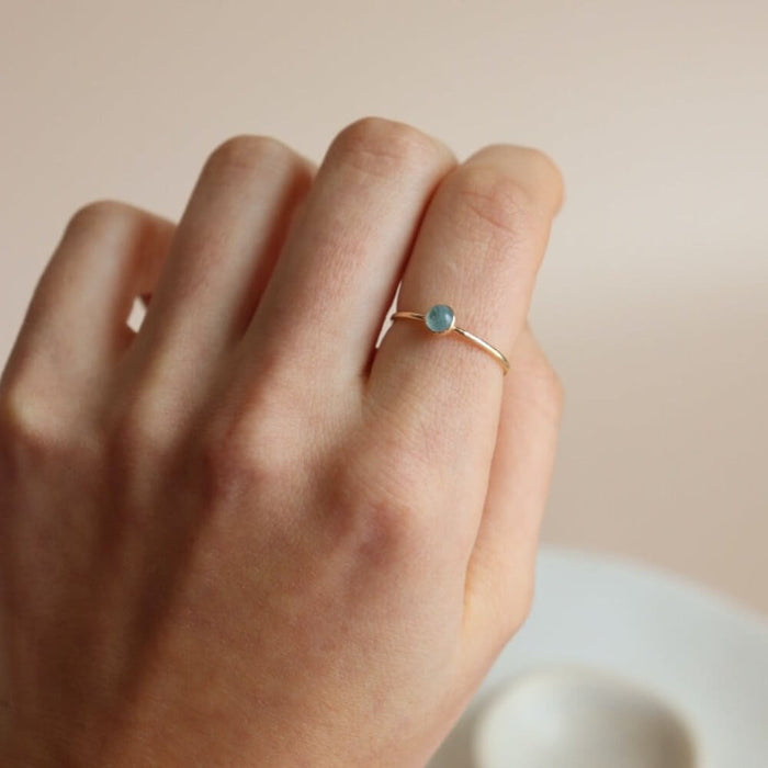 model wearing 14k gold fill bezel ring with 4mm aquamarine stone