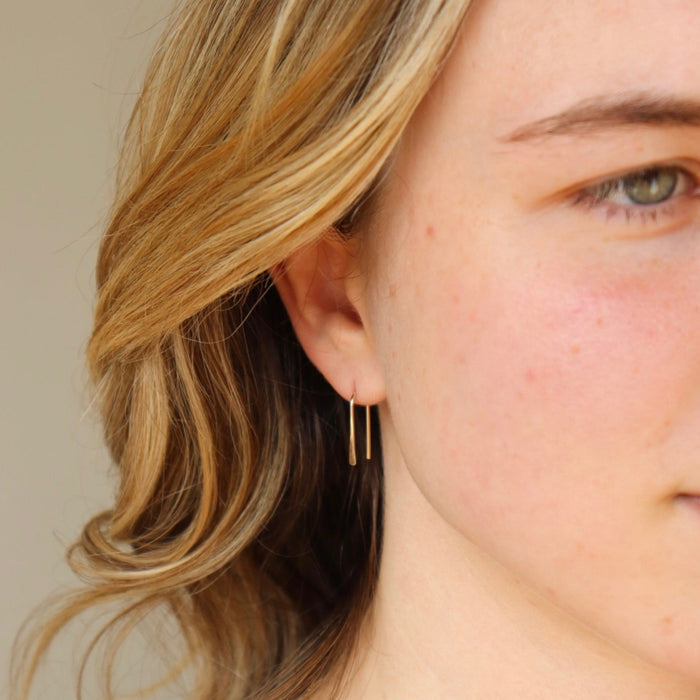 14k solid gold arch earrings shown on a model