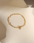gold paperclip chain bracelet with toggle clasp in the sunlight on a light surface
