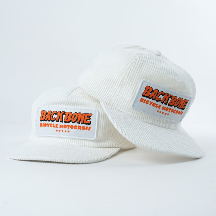 Two white Backbone 5 Star Snapback Hats with flat brims, each featuring a "BACKBONE BICYCLE MOTOCROSS" patch on the front. One hat is slightly stacked over the other.