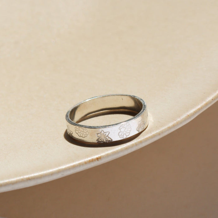 sterling silver cigar band with floral stamping on a light dish