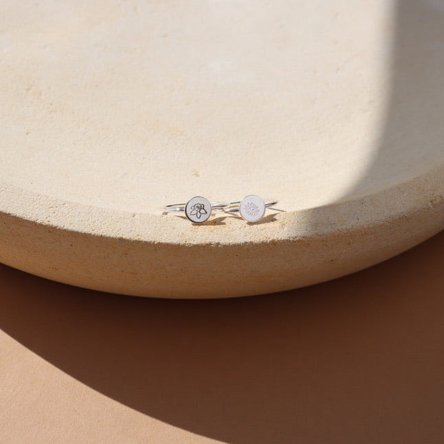 sterling silver delicate band rings with round floral stamped accent on a light dish