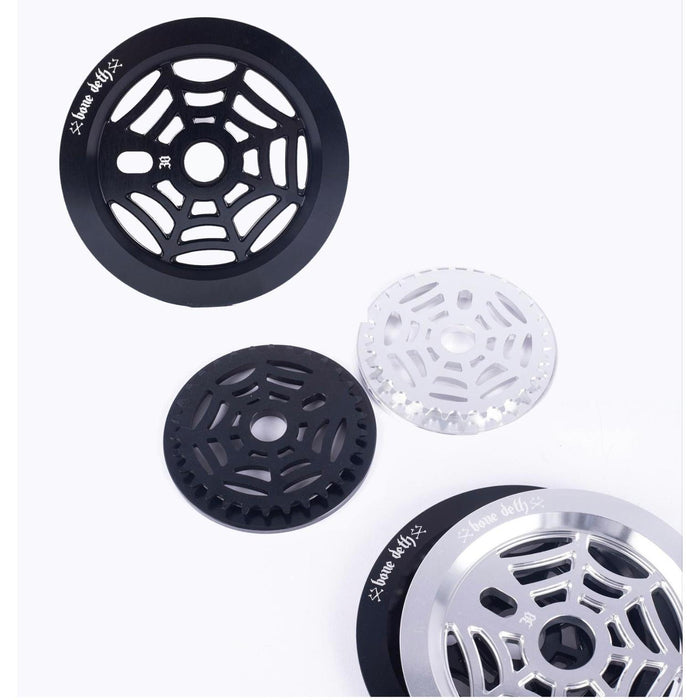 Four BMX sprockets, featuring the Bone Deth Webslinger design, are set against a white background. Each displays unique web-like patterns and vibrant colors, enhancing your ride's style.
