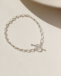 Sterling Silver Brooklyn Toggle Bracelet featuring elongated chain links and a front toggle clasp, styled on a neutral surface in natural light.