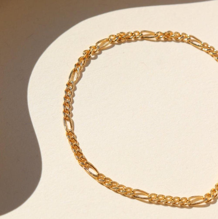 14k gold fill figaro chain bracelet on a light background