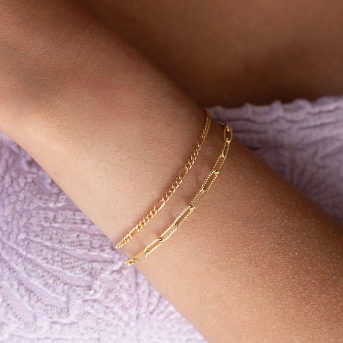 model wearing a 14k gold fill figar chain bracelet paired with a textured 14k gold fill paperclip chain bracelet