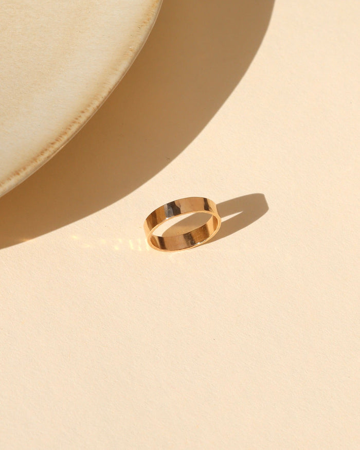14k gold fill lightly hammered thick band ring on alight surface