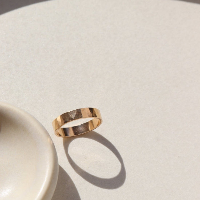 14k gold fill hammered band ring on a light surface