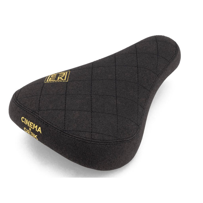 The Cinema CEEK 2 Stealth Pivotal Seat is a black bike seat with quilted stitching, yellow "Cinema" and "OGK" branding, and a durable microfiber cover.