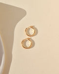 smooth 14k solid gold hoop earrings laid in the sunlight