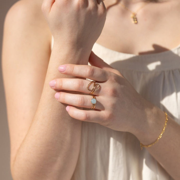 model wearing 14k gold fill sculptural ring with double banded ring with round stone in the sunlight