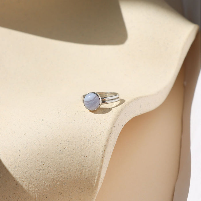 sterling silver double band bezel ring with round blue lace agate stone on a light dish