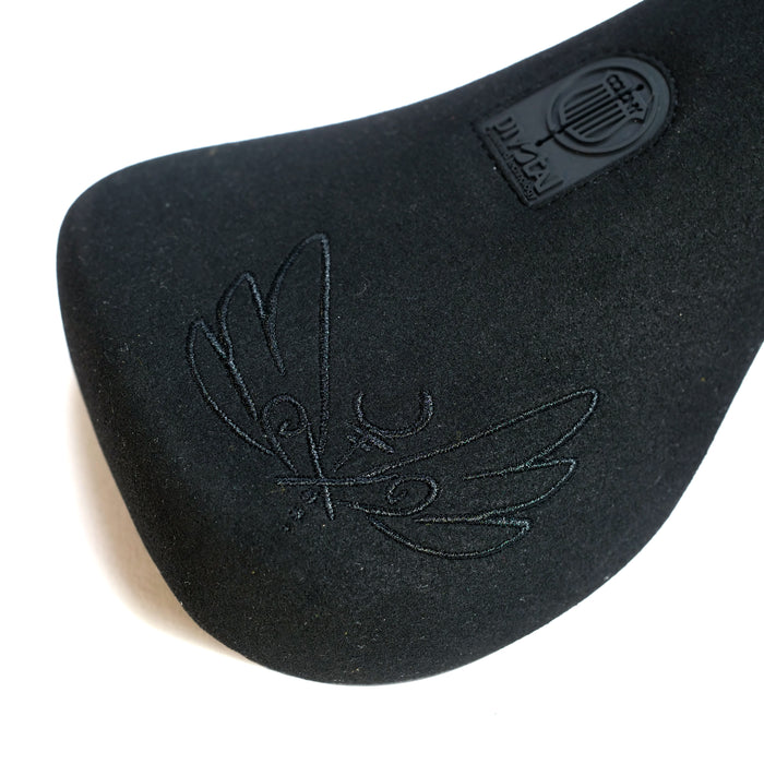 Close-up of the black Colony Sigil Pivotal Seat (Sean Gardner Signature), featuring an embossed bird, crescent moon, stamped logo with text and lyre symbol—an elegant signature BMX seat design.