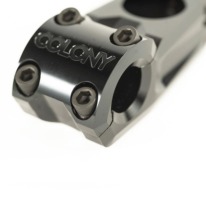 Close-up of a black metal low-rise BMX stem with hex bolts and the brand name “Colony” engraved on the front, highlighting the sleek design of the Colony Variant 52mm BMX Stem (22.2mm Clamp).