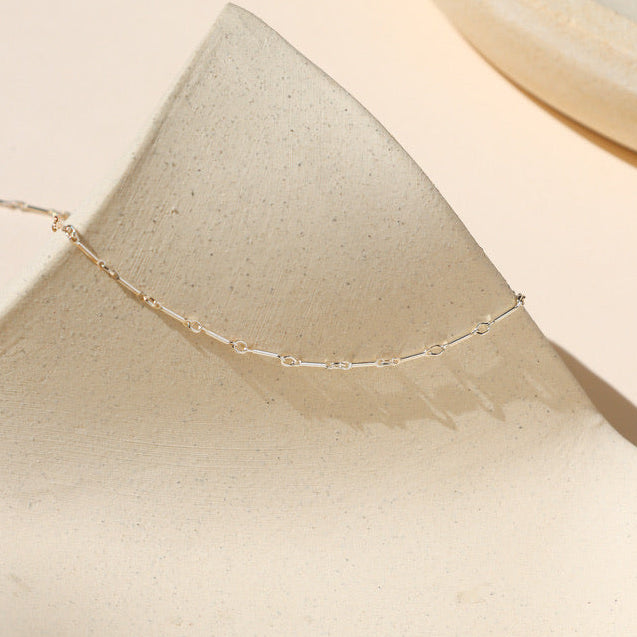 bar and loop chain in sterling silver on a light dish