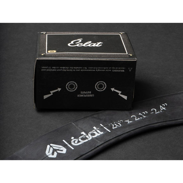 A black Eclat branded box is positioned next to a partially visible Eclat Solo SV Inner Tube (Each), labeled “Eclat 20” x 2.1”-2.4” Schrader valve,” on a dark surface, showcasing this quality 20″ bike tube.