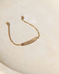 14k gold fill engraved bar and chain bracelet on a light dish