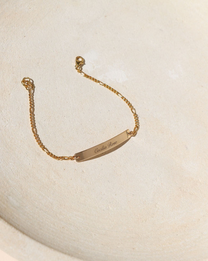 14k gold fill engraved bar and chain bracelet on a light dish