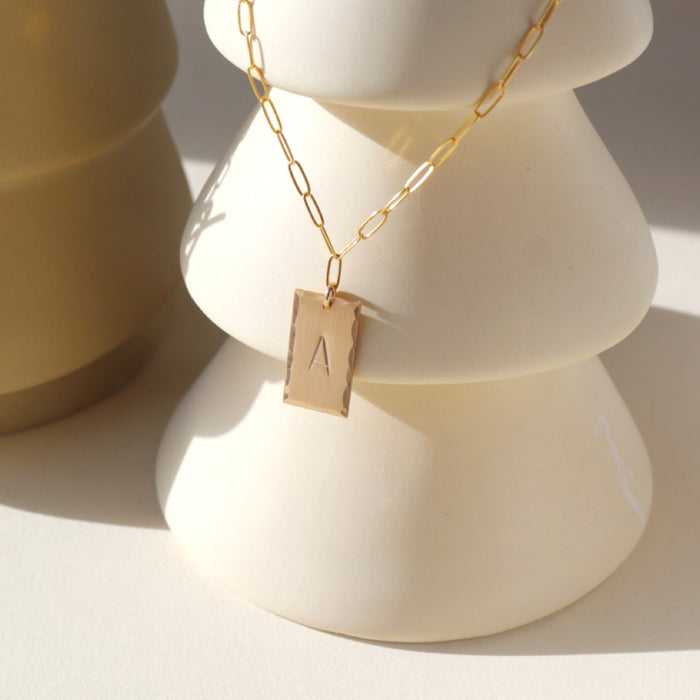 14k gold fill hand stamped pendant on a paperclip chain necklace on a light vase