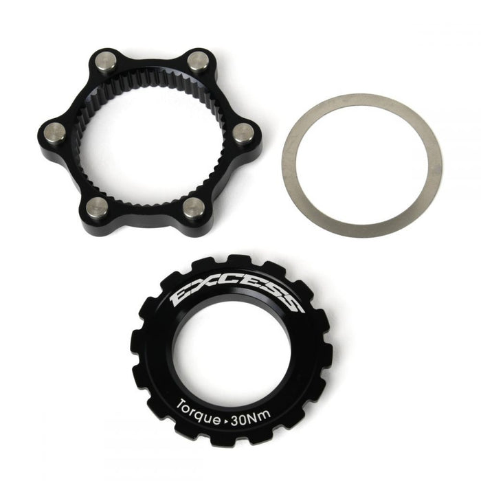 Three cyclocross bike components: a black sprocket marked “EXCESS” and “Torque 30Nm”, a toothed black ring, and a thin gray washer, arranged against a white background. Perfect for customizing your ride with the Excess Centerlock ISO Adapter Kit or upgrading to a 6-bolt disc brake rotor system.