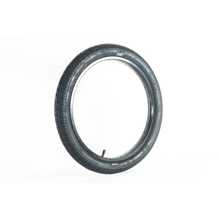 The Family BMX F603 18 Inch Tyre, black and fitted with a valve stem, stands upright against a plain white background, highlighting its versatile tread pattern.
