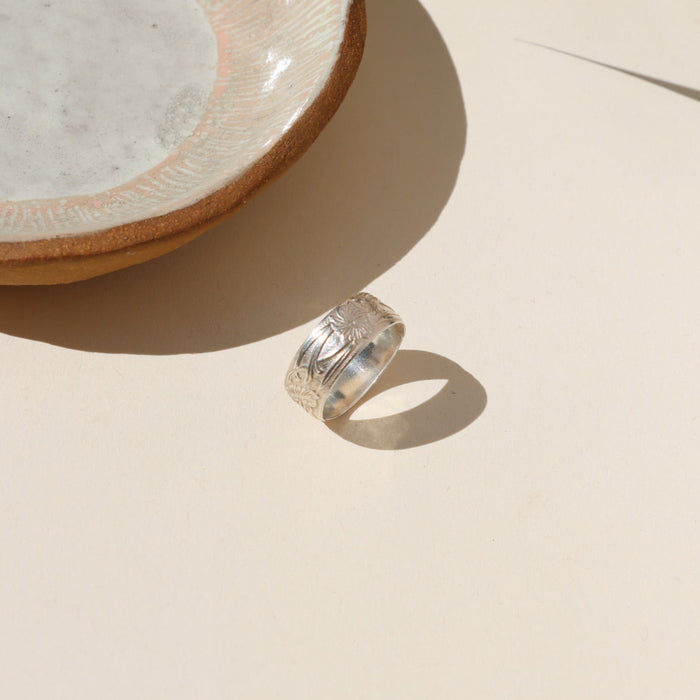 sterling silver textured band ring on a light surface