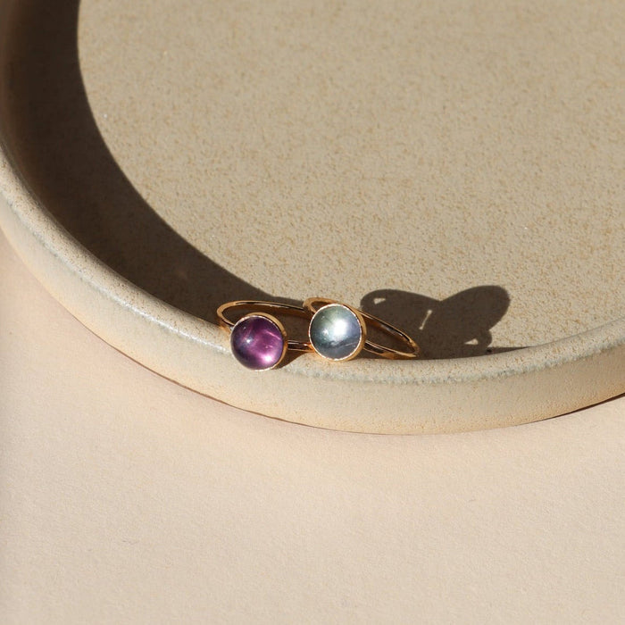2 14k gold fill rings with round fluorite stones on a light dish