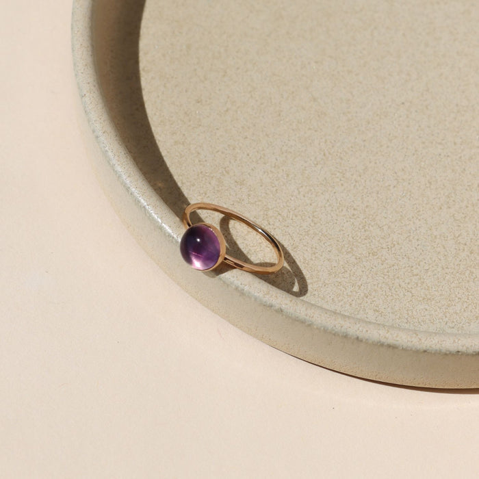14k gold fill ring with round fluorite stone on a light dish