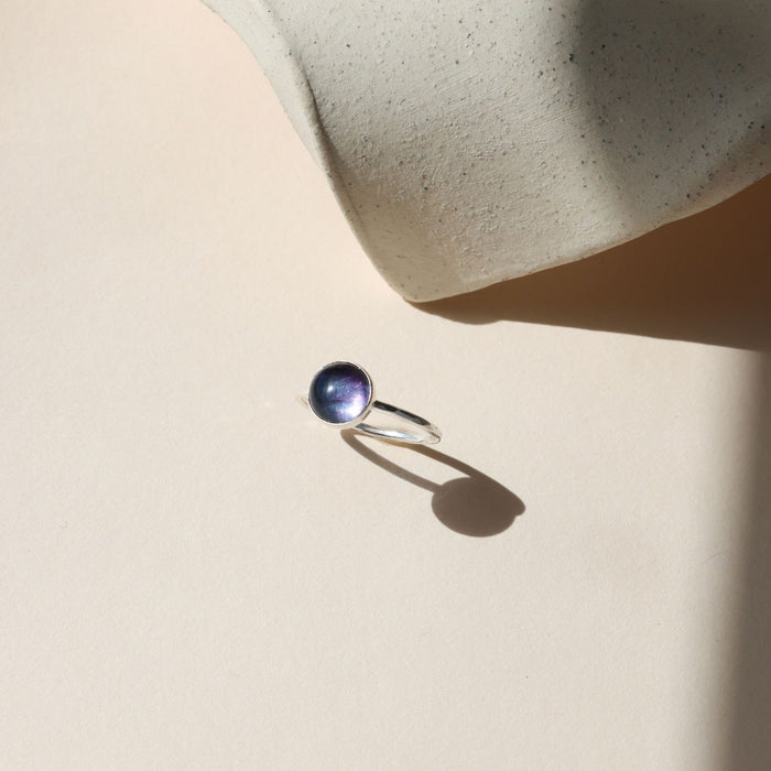 sterling silver ring with round fluorite stone on a light dish