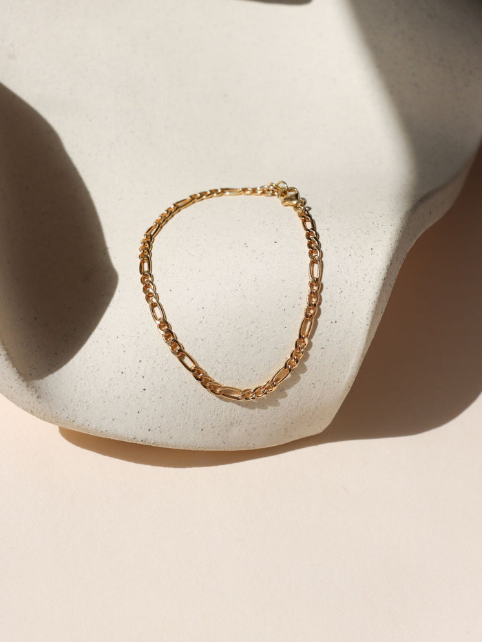 14k gold fill figaro chain bracelet on a light dish