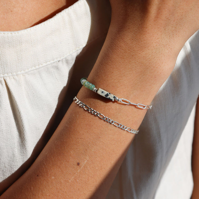 Sterling Silver Figaro Chain Bracelet stacked with a half and half chain and gemstone bracelet on a model