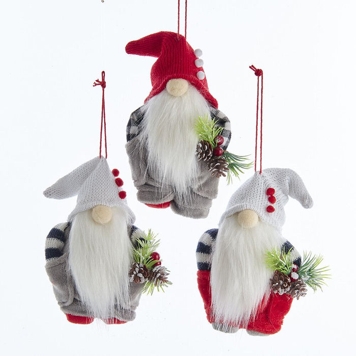 Three festive gnome ornaments with red hats and white beards, holding pine cones and sprigs of holly, on a white background.