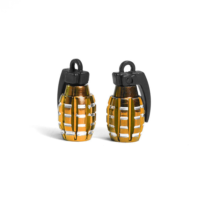 A pair of small gold and black Grenade Valve Caps, designed with a Schrader valve, stand upright on a white background. These unique accessories add both style and functionality to your wheels.