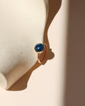 14k gold fill ring with round blue stone on a light dish