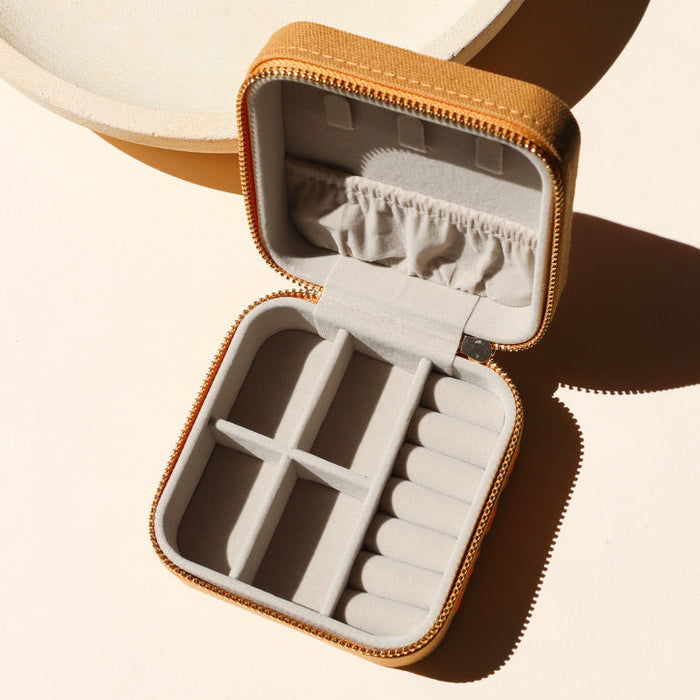square travel jewelry case opened on a light background