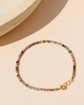tiny agate beaded bracelet with gold accents on a light surface in the sunlight