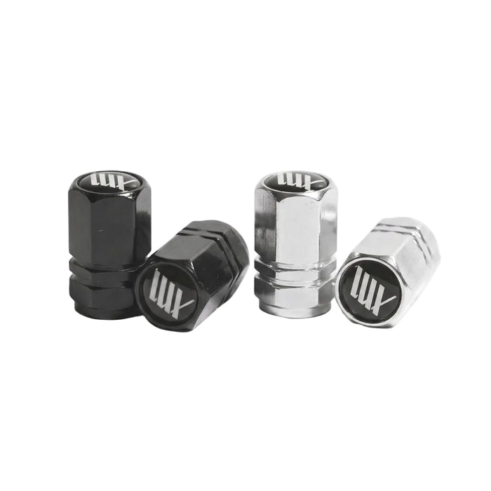 Two pairs of LUXBMX Hex Logo Alloy Valve Caps—one black, one silver—are displayed on a white surface, each showcasing the signature "LUX" logo found on premium LUXBMX accessories.