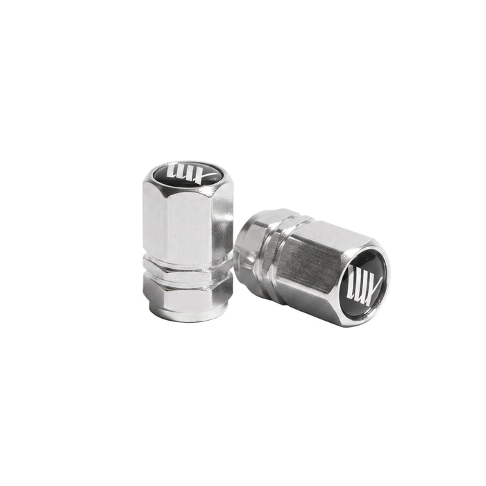 The LUXBMX Hex Logo Alloy Valve Cap (Pair) features two silver hexagonal alloy caps with a black and white "LUX" logo, perfect as stylish bike accessories, shown on a white background.