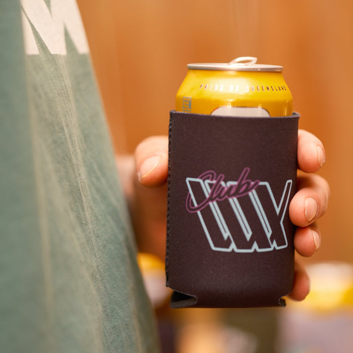 A person in a green shirt holds a yellow can in a black LUXBMX Stubby Cooler featuring the "Club LUX" logo.