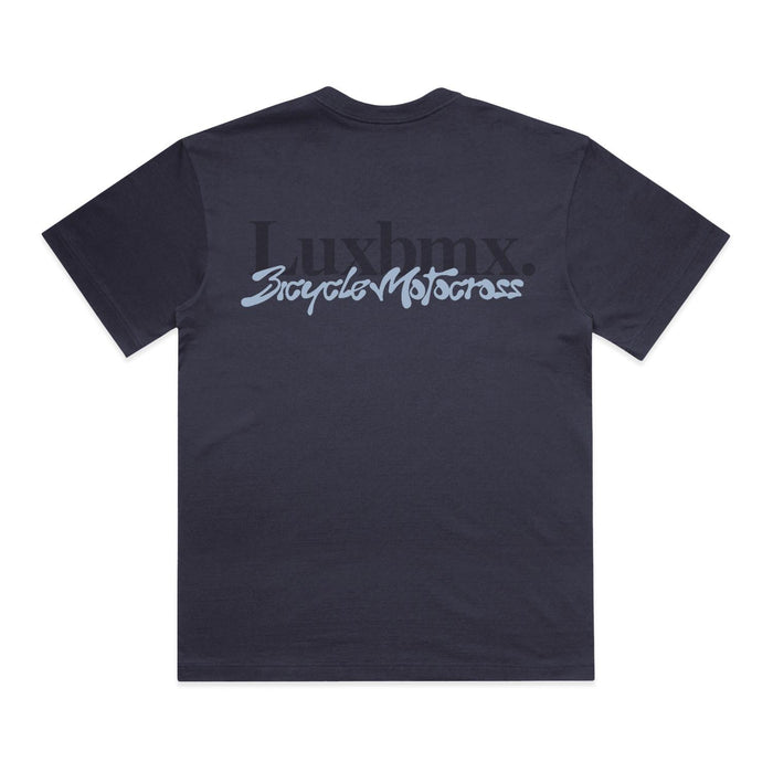 The LUXBMX Times Neue Tee Ink Blue is a heavyweight cotton t-shirt in navy, featuring "Luxbmx." and "Bicycle Motocross" printed boldly on the back in black and light blue fonts, centered near the shoulders—a classic LUXBMX tee style.