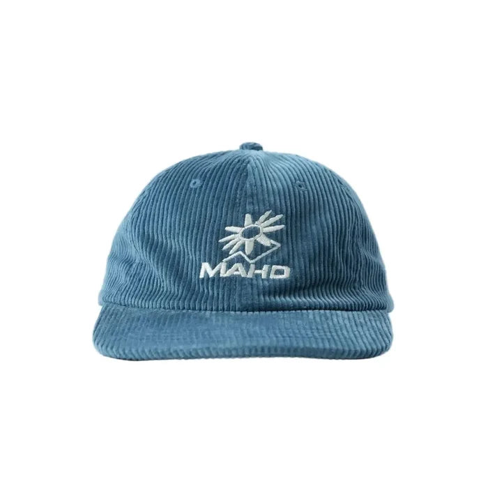 The Mahd Botanical Corduroy Hat—a blue cap featuring a white embroidered sunburst and "MAH·D" text—adds standout style to your look, inspired by Boyd Hilder. Shown on a plain white background.