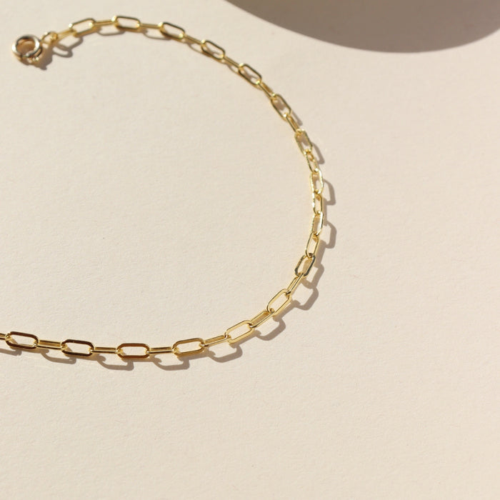 14k gold fill delicate paperclip chain anklet on a light surface