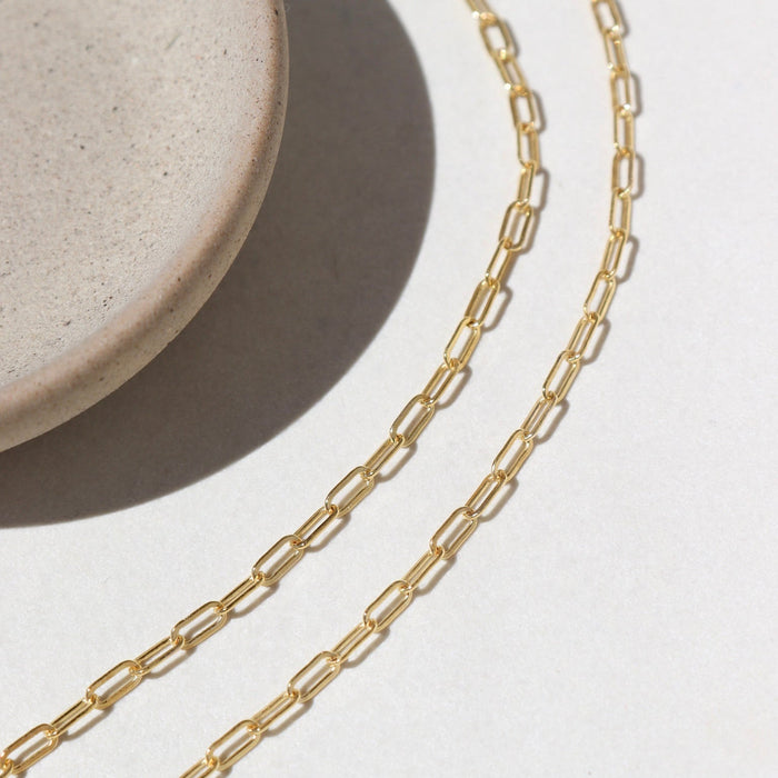 14k Gold fill Narrow Links chain laid on a white paper in the sunlight.