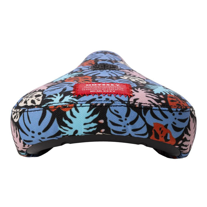 The Odyssey Tropical V1 Pivotal Seat sports sublimated tropical leaf artwork in blue, pink, orange, and black, finished with a stitched red label for vibrant style and island vibes.