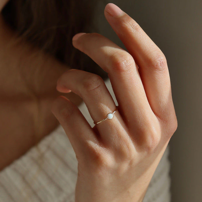model wearing 14k gold fill bezel set ring with 4mm opal stone in the sunlight